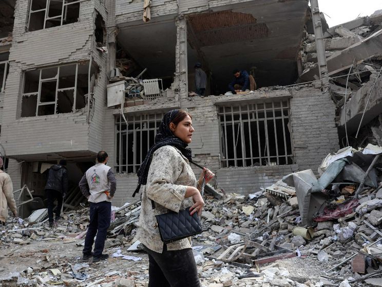 Una donna davanti a un edificio distrutto a Teheran