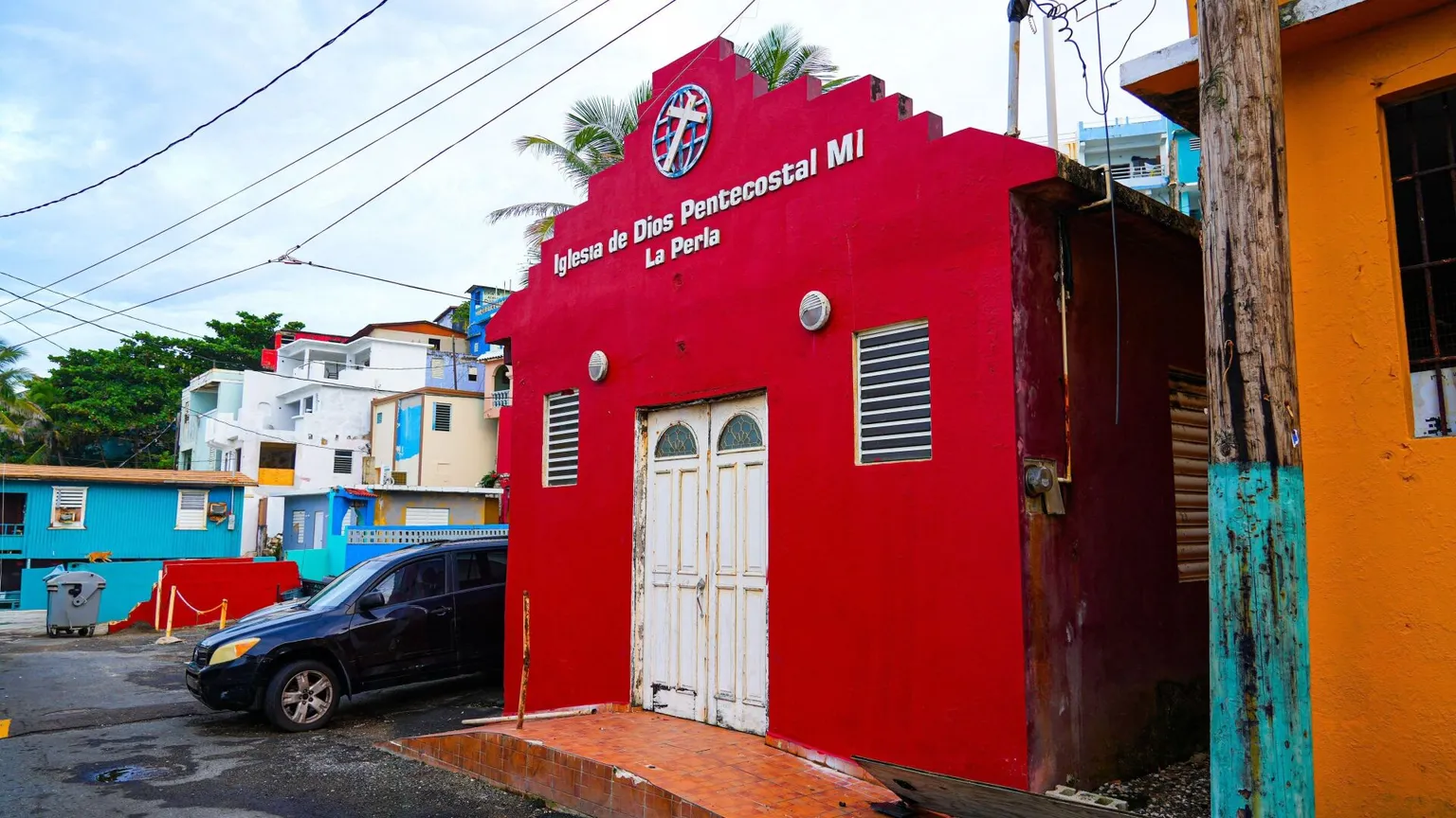 Una chiesa rossa in un quartiere con case colorate