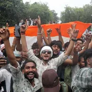 Giovani indiani con le braccia al cielo e il sorriso, davanti a una bandiera dell'India
