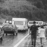 Una foto del 1996 scattata al confine tra Italia e Austria. Una coppia passeggia lungo la strada, bloccata da file interminabili di auto