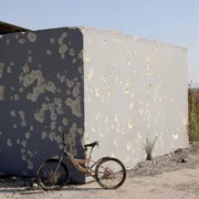 Una bicicletta appoggiata alla parete crivellata di proiettili di un rifugio antiaereo in cemento, fuori dal kibbutz Nahal Oz