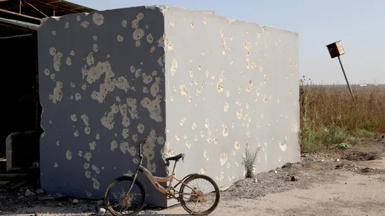 Una bicicletta appoggiata alla parete crivellata di proiettili di un rifugio antiaereo in cemento, fuori dal kibbutz Nahal Oz