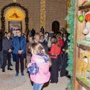 Bambini e adulti chiacchierano e sorridono in una piazzetta davanti alla chiesa addobbata con luci e decorazioni natalizie