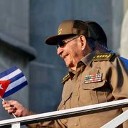Un uomo si sporge da un parapetto con una bandiera cubana in mano. Si tratta di Raul Castro, ex presidente cubano