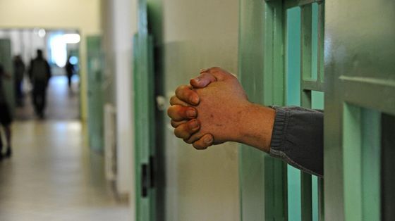Due mani che sporgono dalle sbarre di un carcere