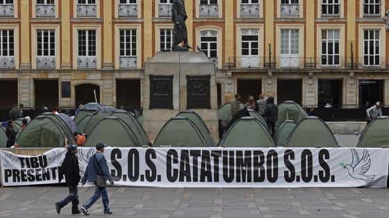 Due persone passano davanti a una serie di tende nella piazza Bolívar di Bogotà e alla scritta: "S.O.S. Catatumbo". Con l'iniziativa, i promotori hanno voluto denunciare la violenza nella regione ocolombiana