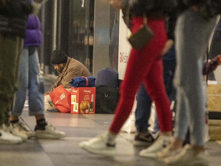 Un clochard dorme in strada, nel centro di Milano