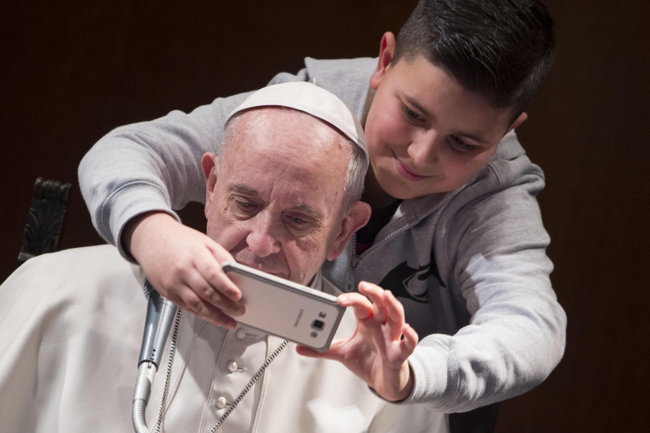 Un bambino si fa un selfie con papa Francesco durante un'udienza