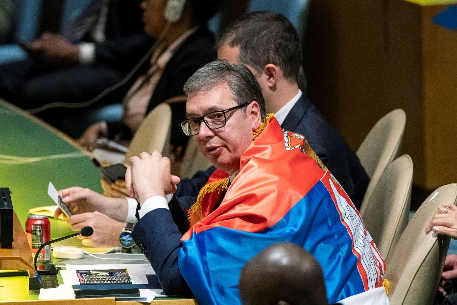 Il presidente serbo Vucic avvolto nella bandiera serba attende l'esito della votazione all'Onu