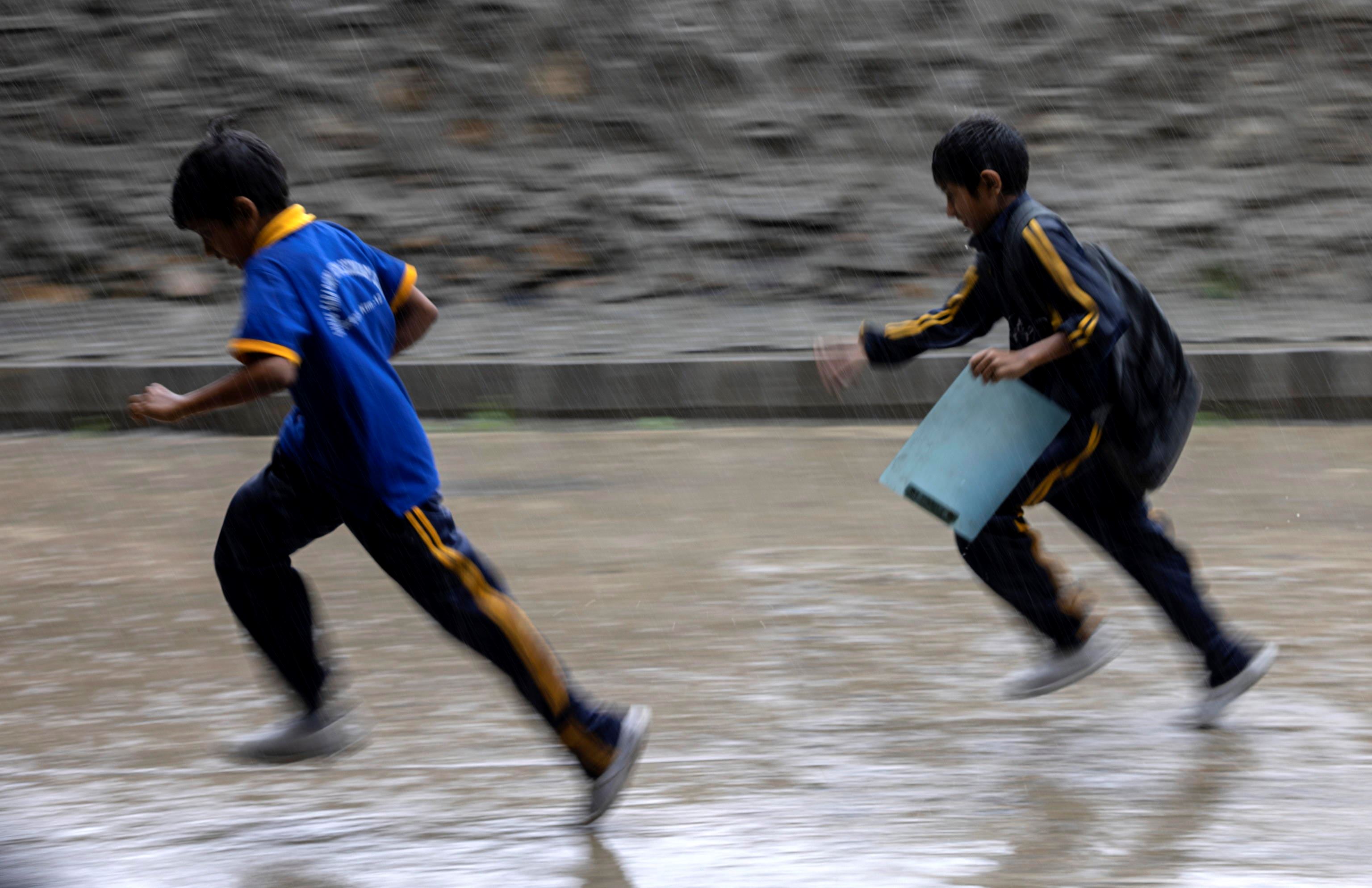 Bambini  giocano sotto la pioggia a Kathmandu