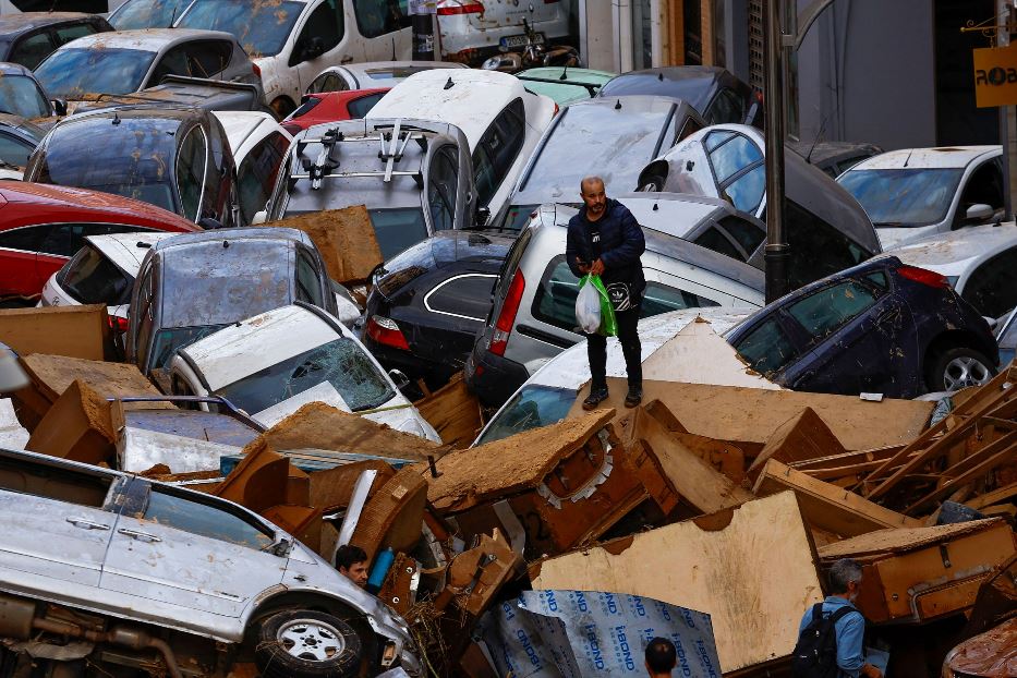 Le persone si muovono stralunate tra pile di automobili per le strade di Valencia