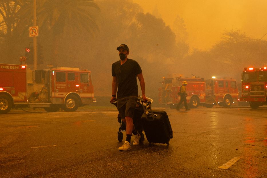 Un residente di Pacific Palisades lascia il quartiere, avvolto dai fumi dell'incendio