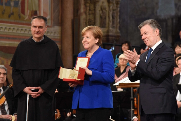 La cancelliera Angela Merkel con il presidente Juan Manuel Santos (a destra) e padre Mauro Gambetti (Ansa)