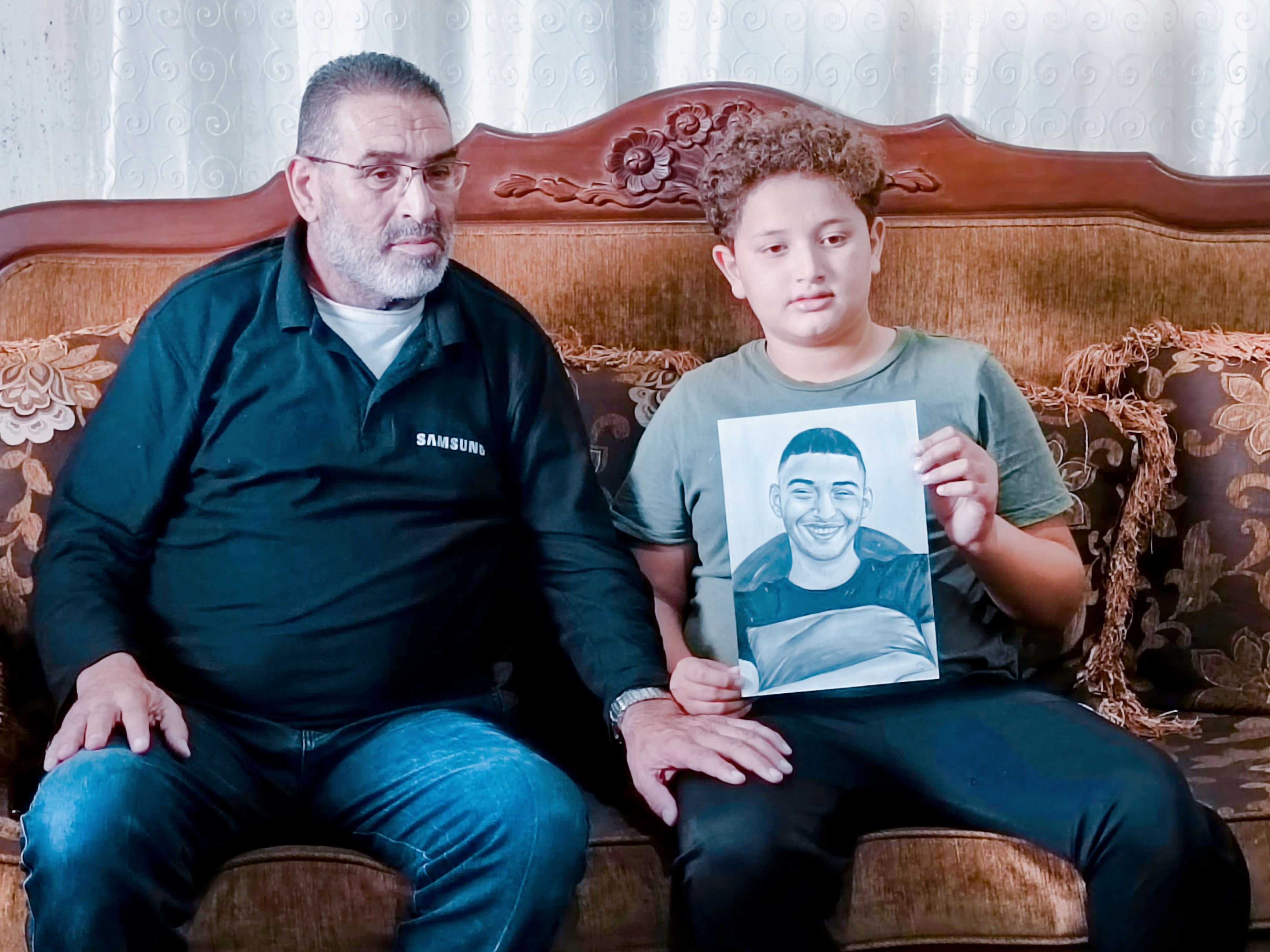 Mohammad con il figlio Ibrahim, mostrano il ritratto di Jamal, ucciso a 15 anni