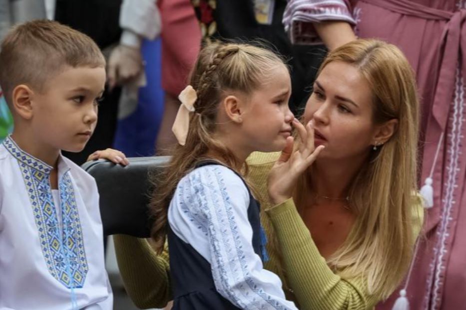 Una bambina ucraina piange, il primo giorno di scuola, consolata dalla mamma