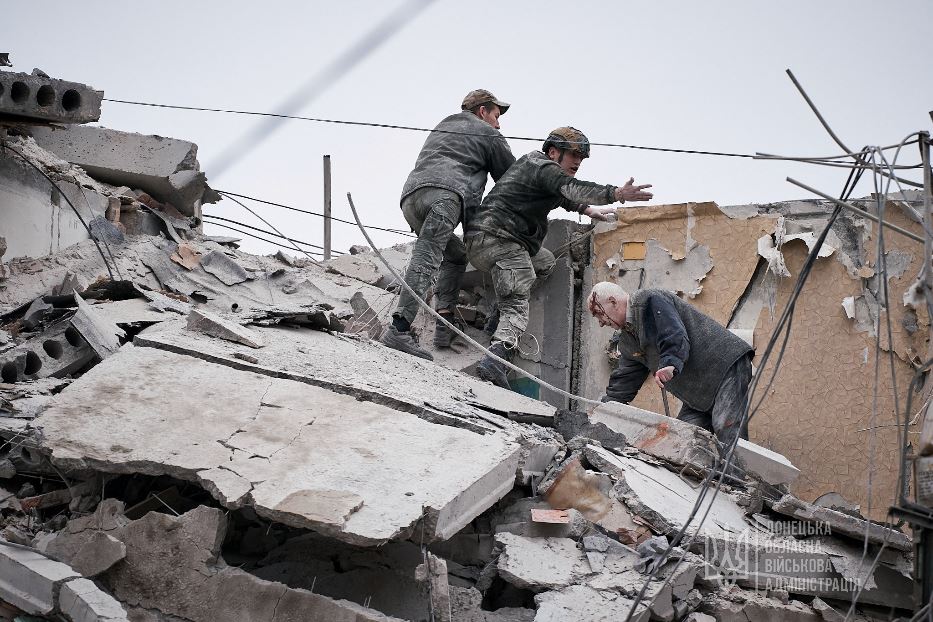Militari proteggono un ferito tra le macerie di un edificio danneggiato da un attacco russo, a Sloviansk, nella regione di Donetsk