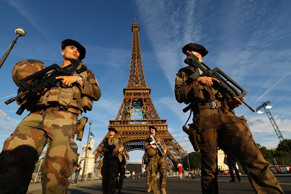 Soldati francesi pattugliano la Torre Eiffel decorata con i cinque cerchi olimpici