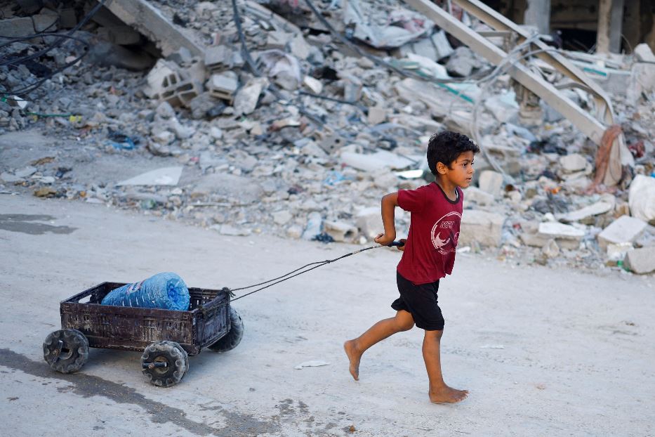 Un bambino palestinese traina un contenitore di acqua potabile, su un carrettino improvvisato, nel sud di Gaza City