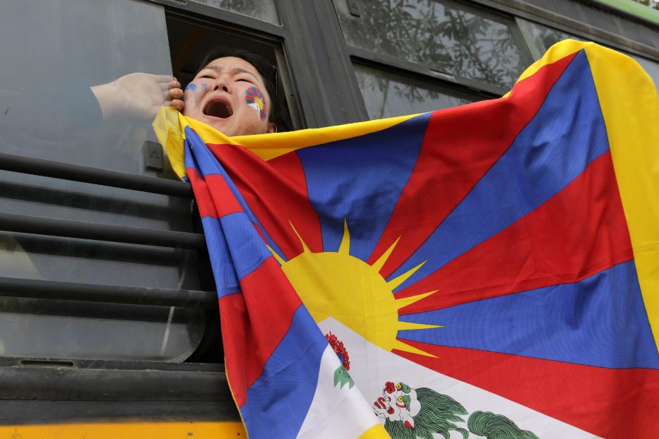 Un'attivista del Tibetan Youth Congress esibisce una bandiera tibetana dopo essere stata arrestata davanti all'ambasciata cinese a Nuova Delhi, in India