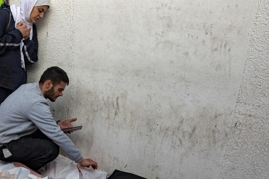 Alcuni palestinesi cercano i propri cari fra i corpi senza identità accatastati a terra a Rafah