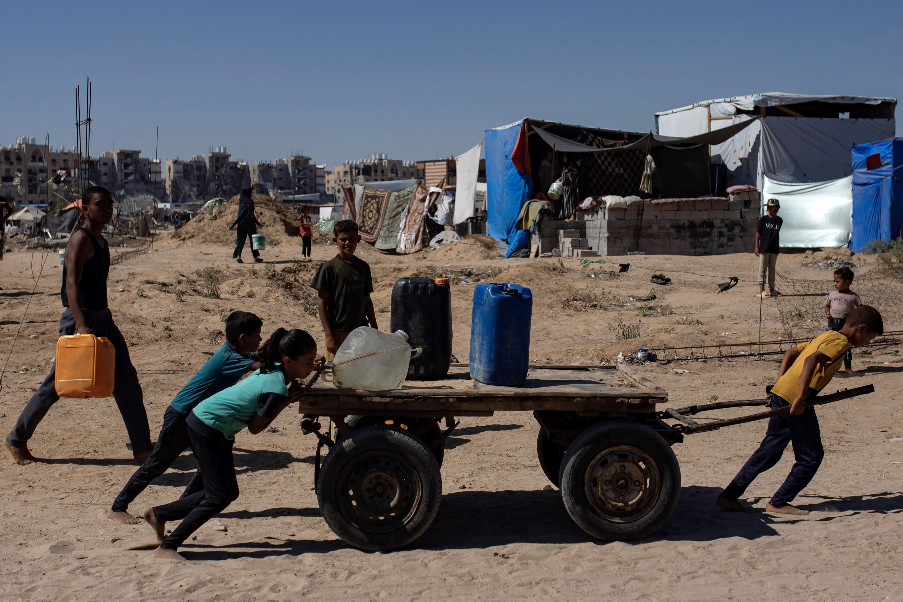 Bambini palestinesi trasportano acqua potabile a Khan Yunis