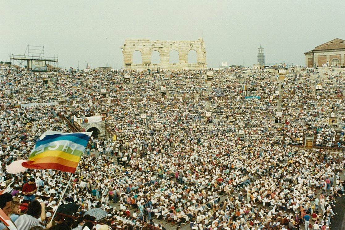 1986. Alla prima arena di Pace, don Tonino Bello esprime la convinzione assoluta che la pace sia possibile solo insieme alla giustizia e alla salvaguardia del creato. «Finché per secoli nelle nostre Chiese abbiamo parlato di pace, nessuno ha contestato. Ma quando si è scoperta la stretta parentela che c’è tra la pace e la giustizia, si sono scatenate le censure dei potenti. Si è asserito e si continua ad asserire che collegare il discorso sulla pace con i discorsi sull’economia perversa che domina il mondo, sul profitto, sulla massimizzazione del profitto, sui debiti del terzo mondo, sulla crescente divaricazione tra il Nord della terra e il Sud, significa fare la parte degli utili idioti. La giustizia collocata da Dio stesso accanto alla pace desta più sospetto di quanto non desti scandalo collocata accanto alla guerra, tant’è che si parla ancora di “guerra giusta”. Questa si che è una convivenza contro natura!». - Archivio Arena di Pace