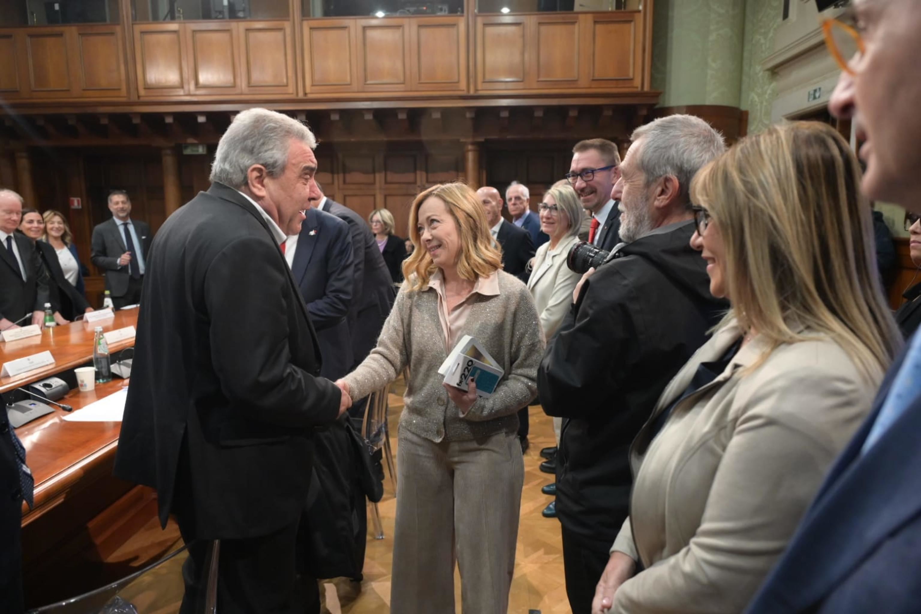 Giorgia Meloni saluta Luigi Sbarra, leader Cisl, con in mano i "regali" portati alla premier dai segretari di Cgil e Uil