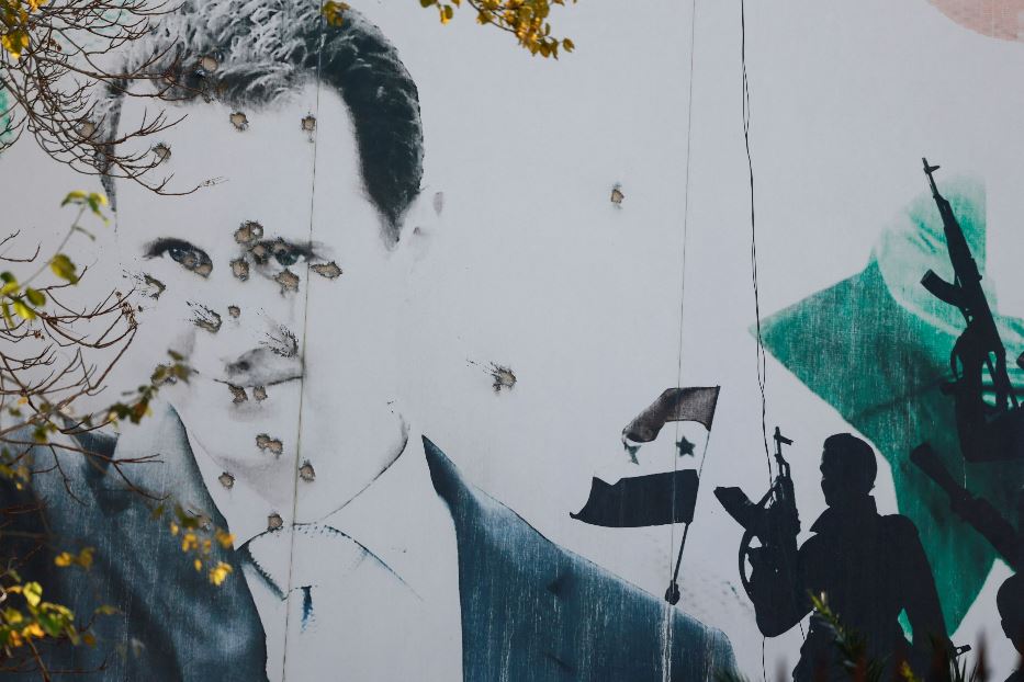 Un murales di Assad trivellato di colpi a Damasco