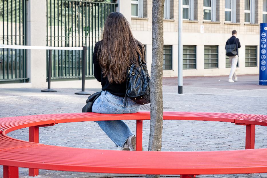 Una ragazza sulla panchina rossa davanti alla Bocconi di Milano