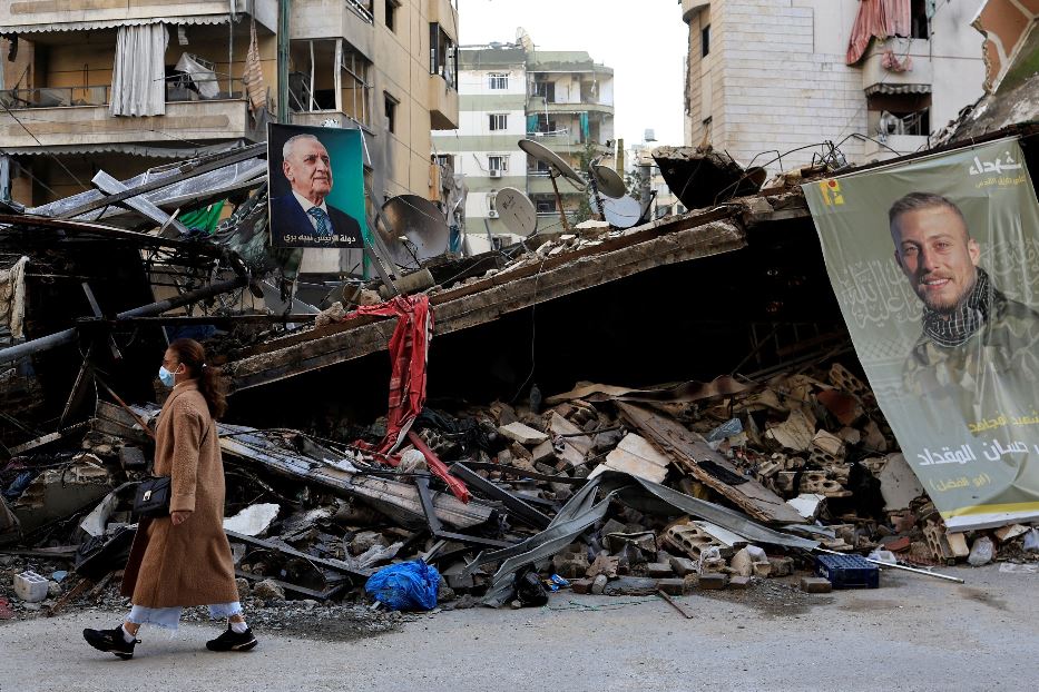 Una donna cammina davanti a un edificio in macerie in un sobborgo di Beirut