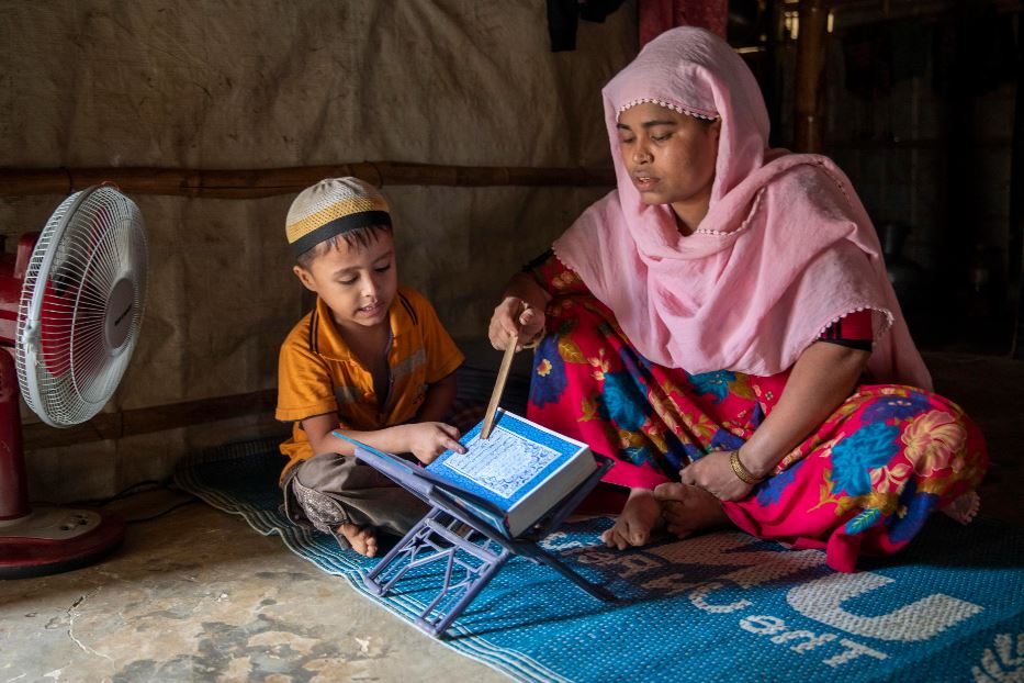 Una madre insegna il Corano al figlio in un campo di profughi Rohingya in Bangladesh