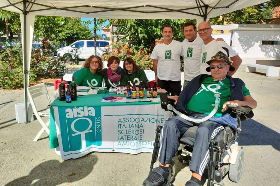 Lo stand in una piazza per un’edizione della Giornata nazionale Sla, con un malato e alcuni volontari di Aisla