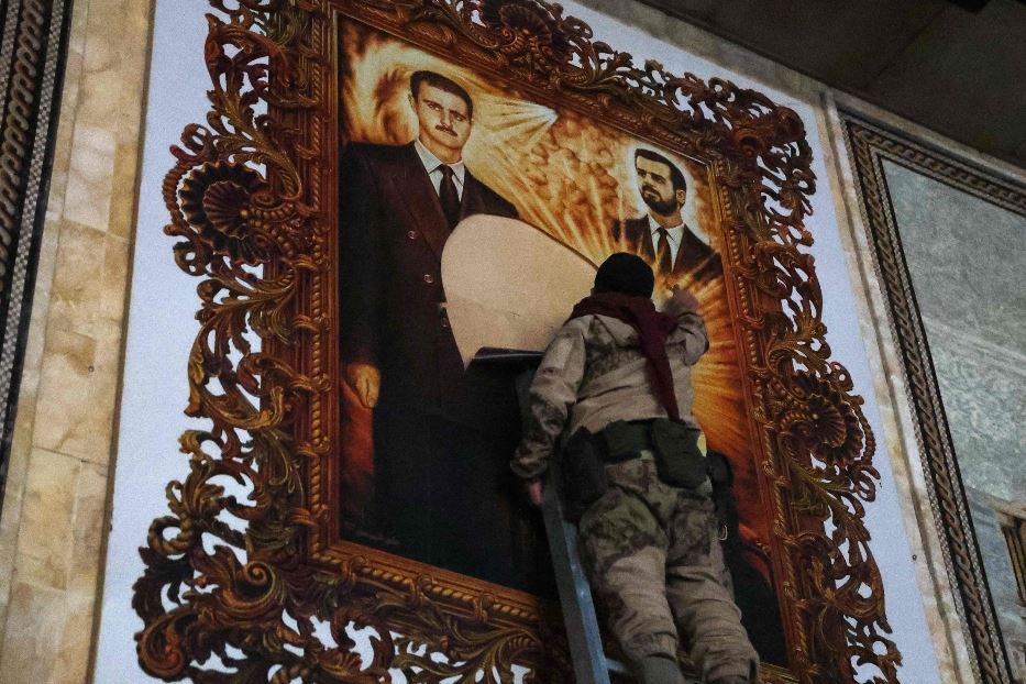 Un combattente antiregime strappa una gigantografia raffigurante il presidente siriano Bashir al-Assad e suo fratello Maher all'aeroporto di Aleppo