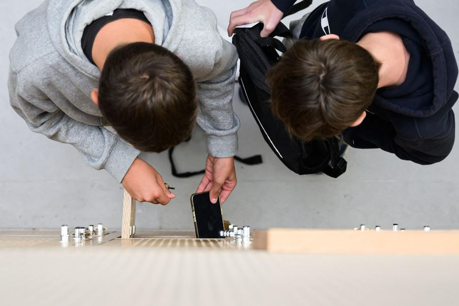 Due studenti sistemano il loro smartphone nell'armadietto in una scuola francese. Oltralpe è scattato il divieto dell'uso del dispositivo in 200 scuole medie e si dibatte se non vietarne del tutto l'uso prima dei 13 anni