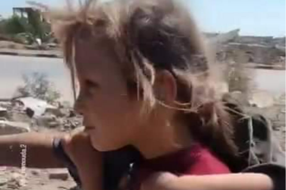 La bambina in fuga da Gaza con la sorellina sulle spalle