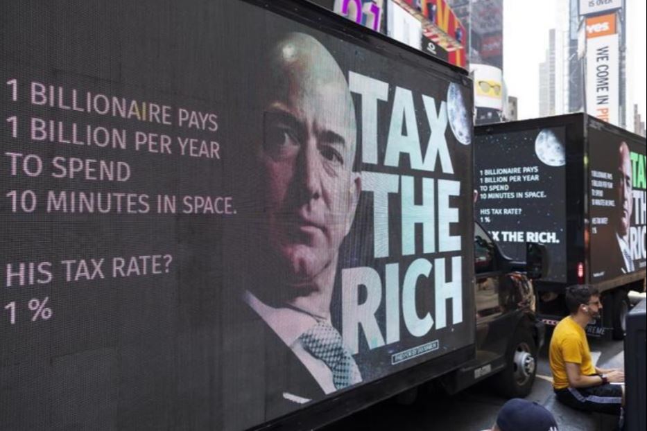 Un camion con un manifesto della campagna "Tax the rich" con la foto del miliardario Jeff Bezos