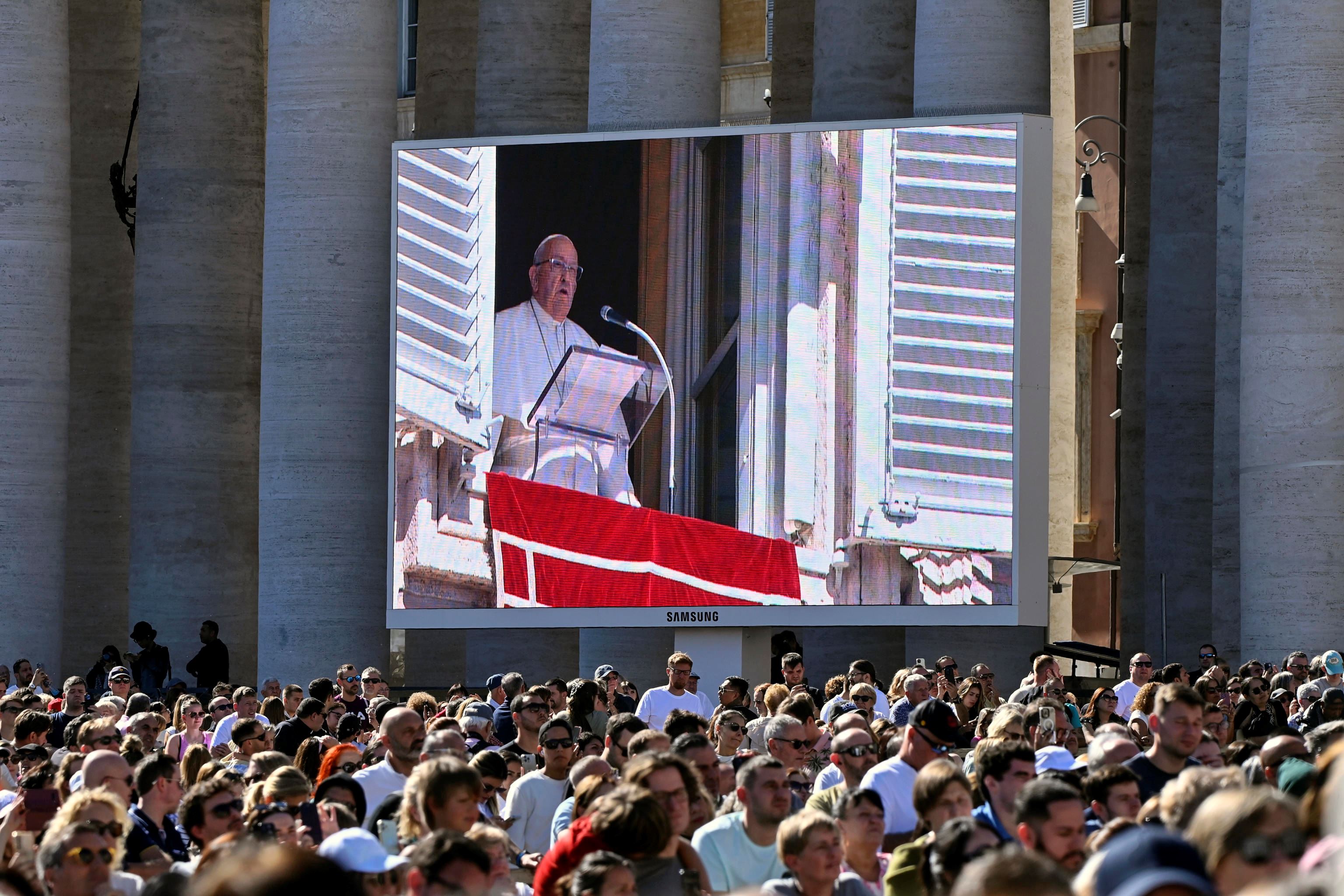 I fedeli davanti al maxischermo di piazza San Pietro partecipano alla preghiera dell'Angelus