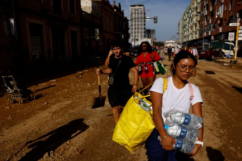 Gli abitanti di Valencia con i viveri per le strade piene di fango