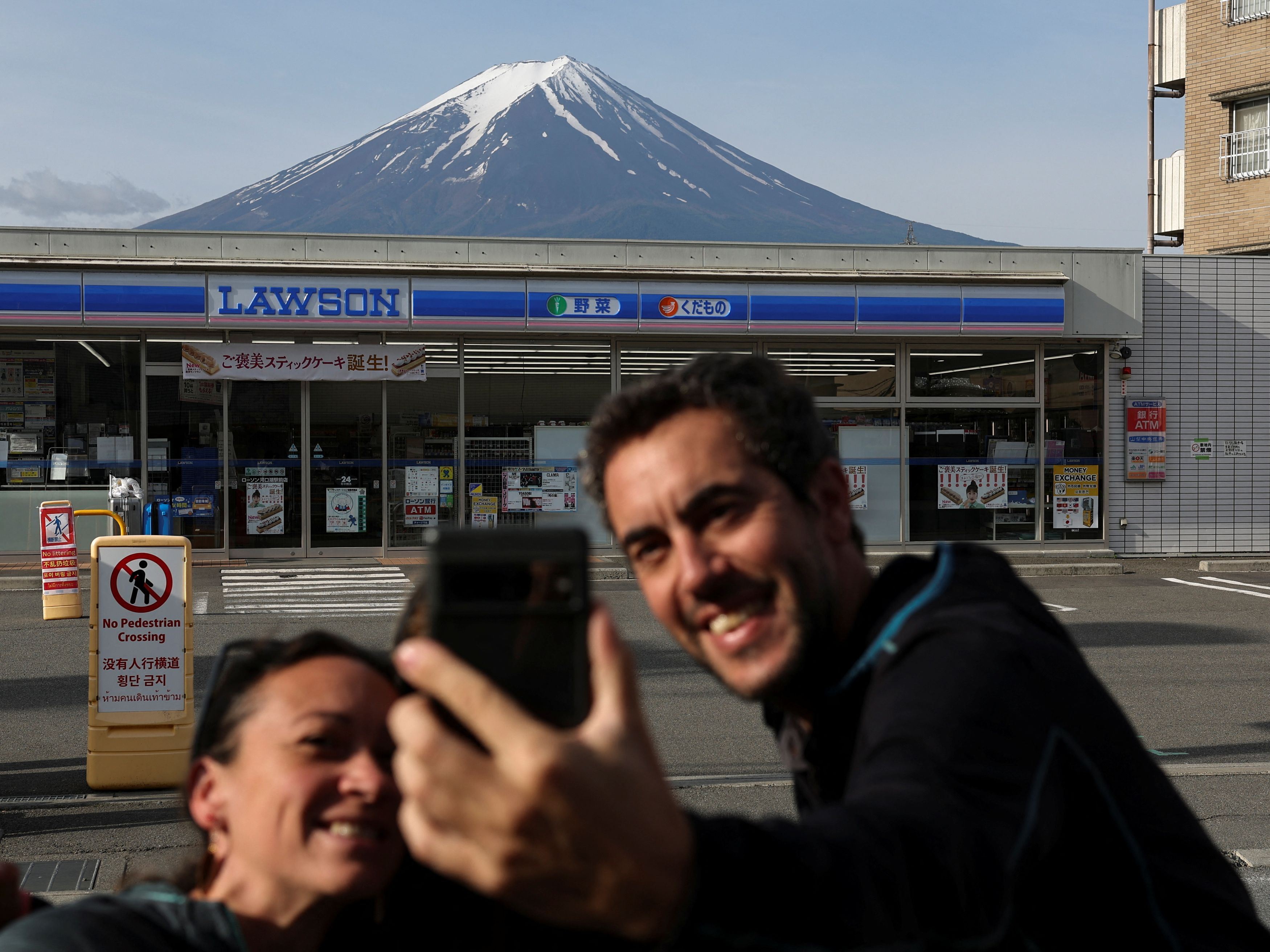 Turisti si fanno un autoscatto con lo sfondo del Monte Fuji a Fujikawaguchiko