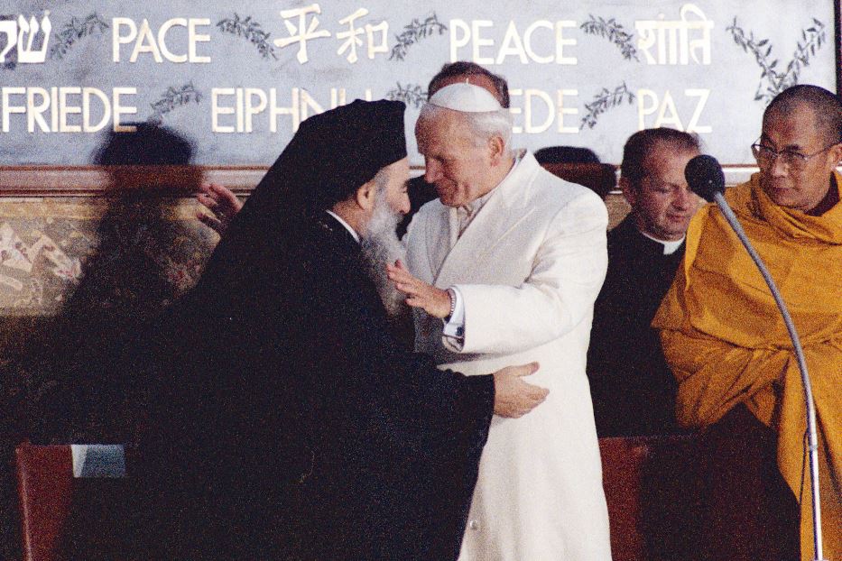 L’incontro di preghiera per la pace tra le religioni ad Assisi, 1986: il Metropolita Filarete di Minsk abbraccia papa Giovanni Paolo II con, accanto, il Dalai Lama