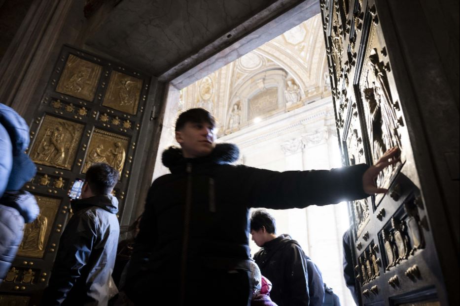 Giovani pellegrini attraversano la Porta Santa nella Basilica di San Pietro