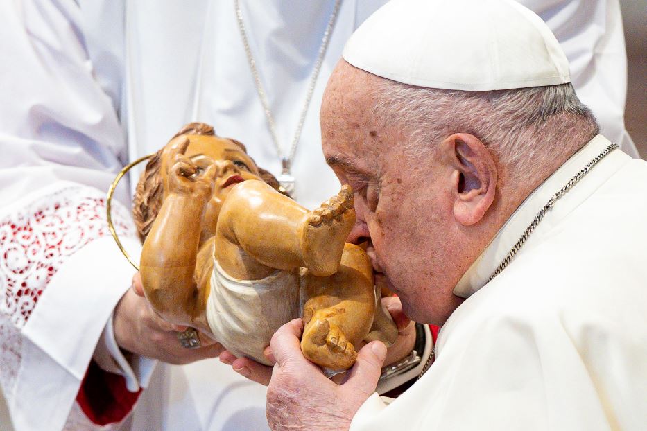 Il Papa bacia la statuetta di legno del Bambin Gesù in San Pietro durante una liturgia nel tempo di Natale